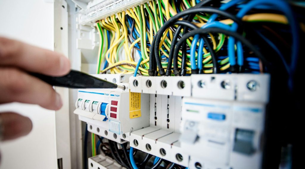 pexels-photo-257736-257736 Hand of electrician working on a circuit breaker panel with colorful wires, ensuring safe electrical connections.